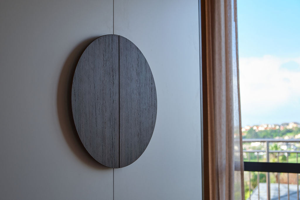 custom made round wooden handles on    Ilse's custom wardrobe with a view of a balcony and greenery outside.