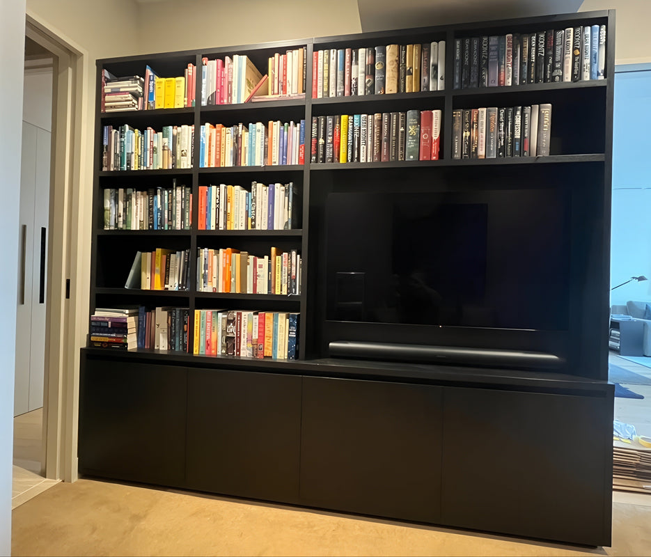 Custom Black Oak entertainment unit with books and a TV in a living room setting. 